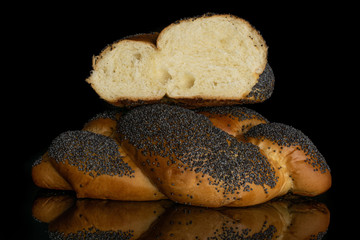 Group of one whole one half of twisted poppy seed bun isolated on black glass