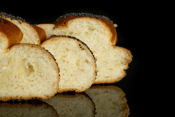 Closeup of three slices of twisted poppy seed bun in row isolated on black glass