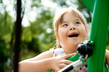 A portrait of trisomie 21 child girl outside having fun on a park