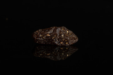 One piece of raisin of lingonberry strawberry fruit tea macro isolated on black glass
