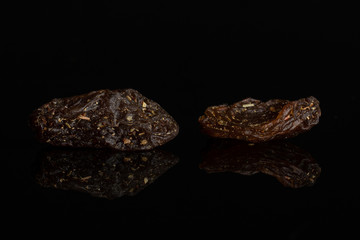 Group of two pieces of raisin of lingonberry strawberry fruit tea macro isolated on black glass