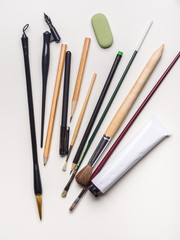 Brushes, pens and pencils on a white background. Flat lay