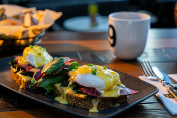 Breakfast with poached egg on toast and coffee and it served on wooden table