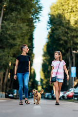 Mother and daughter walking on the street with a dog