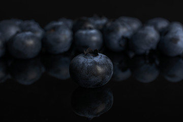 Lot of whole fresh blue bilberry isolated on black glass