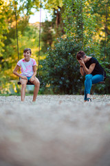 Fototapeta premium Mother and daughter sitting on a swing and laughing
