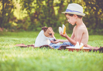 During picnic boy treat domestic dog with bit of melon - obrazy, fototapety, plakaty