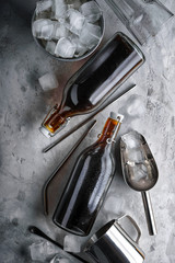 Cold brew coffee in a two glass bottle , metal straw ,scoop, aluminum kettle and ice cube in a metal bucket  on a dark background.