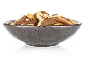 Lot of whole raw brown brazil nut in dark ceramic bowl isolated on white background