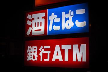 Advertisement sign in Japanese of convenience store at night. Translation : Alcohol, Cigaret and...