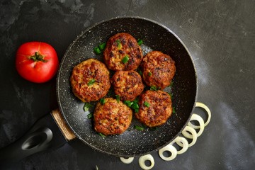 Meat cutlets. Cutlets in a pan on a black concrete table background. Delicious tasty food. Cutlets in the black plate isolated.