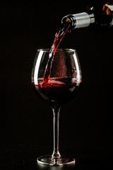 Red wine being poured in a wine glass on a dark background