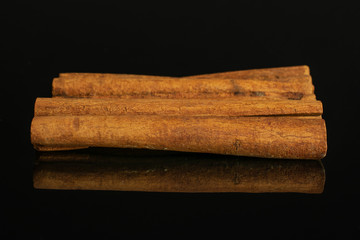 Group of four whole dry brown cinnamon isolated on black glass