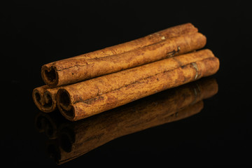 Group of three whole dry brown cinnamon isolated on black glass