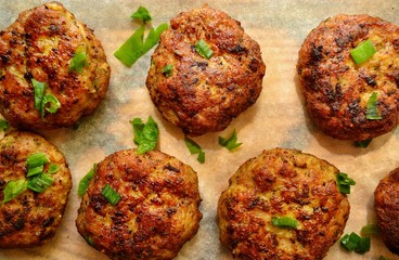 Meat cutlets. Cutlets on a wooden board. Food on a black concrete table background. Food on a board with parchment. Delicious tasty food. Close up.