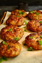 Meat cutlets. Cutlets on a wooden board. Food on a black concrete table background. Food on a board with parchment. Delicious tasty food. Close up.