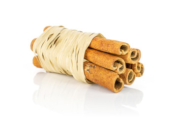 Group of six whole dry brown cinnamon wrapped in natural bast isolated on white background