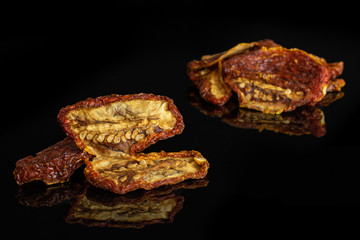 Lot of whole dried red tomato isolated on black glass