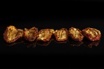 Group of six whole dried red tomato isolated on black glass