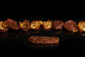 Lot of whole dried red tomato isolated on black glass