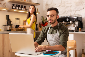 Fototapeta premium Husband working on laptop while owning family business
