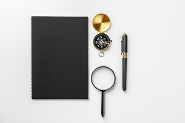 Golden compass with black notepad and pen close up on a table