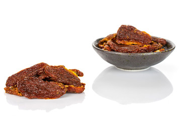 Lot of whole dried red tomato small group is in the back in dark ceramic bowl isolated on white background