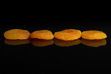 Group of four whole dried orange apricot isolated on black glass