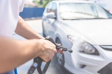 Close up of man washing his car with pressurized water in car wash outdoors.