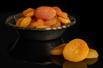 Lot of whole dried orange apricot in metal bowl isolated on black glass