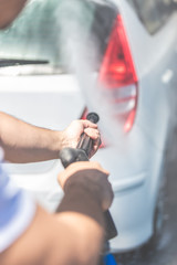 Close up of man washing rear part of the car under high pressure water outdoors.