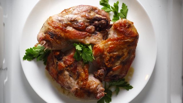Fried boneless chicken legs on a plate rotating in microwave top view.