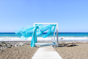 romantic gazebo on the beach with a curtain fluttering in the wind