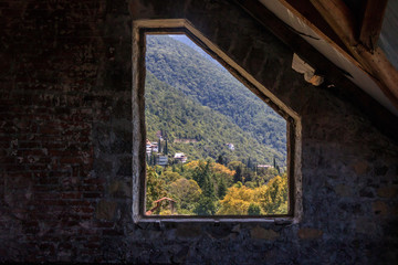 Fototapeta na wymiar view from the old stone window to the mountains and forest