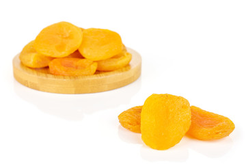 Lot of whole dried orange apricot on round bamboo coaster isolated on white background