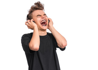 Rebellious happy teen boy with headphones, isolated on white background. Cheerful child listening to music and singing song. Emotional portrait of teenager in style of punk goth enjoying music.