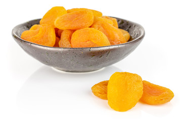 Lot of whole dried orange apricot in dark ceramic bowl isolated on white background