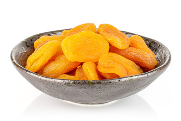 Lot of whole dried orange apricot in dark ceramic bowl isolated on white background