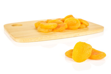 Lot of whole dried orange apricot on bamboo cutting board isolated on white background
