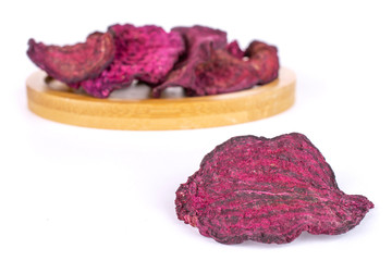 Group of six slices of dried red beetroot on bamboo coaster isolated on white background