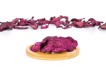 Lot of slices of dried red beetroot on bamboo coaster isolated on white background