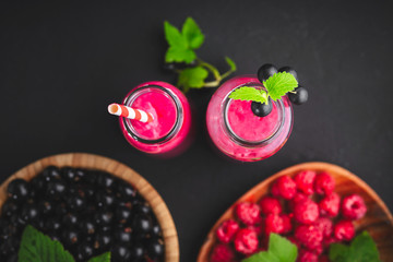 Raspberry and currant berry smoothie in a glass bottle with a straw and mint leaf