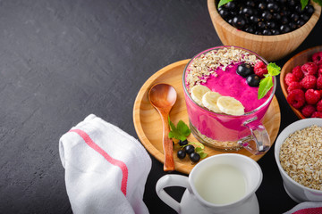 Healthy breakfast,fitness food for diet, Raspberry and currant berry bowl smoothie in a  glass cup with a wooden spoon,mint leaf, oatmeal in white dish