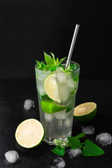 Cocktail Mojito with ice in a glass, lime, leaf mint and metal straw