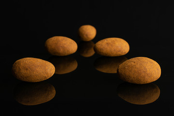 Fototapeta na wymiar Group of five whole sweet brown chocolate cinnamon almond isolated on black glass