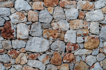 Modern wall of large unprocessed pieces of rock, stones. Background stone wall.