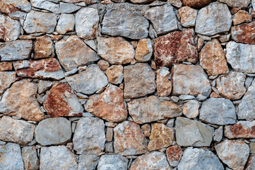 Modern wall of large unprocessed pieces of rock, stones. Background stone wall.