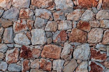 Modern wall of large unprocessed pieces of rock, stones. Background stone wall.