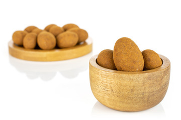 Lot of whole sweet brown chocolate cinnamon almond in tiny wooden bowl on round bamboo coaster isolated on white background