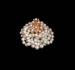 Black pearls and brooch on a white background